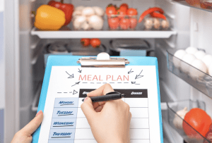 Woman Making Meal Plan in front of Fridge